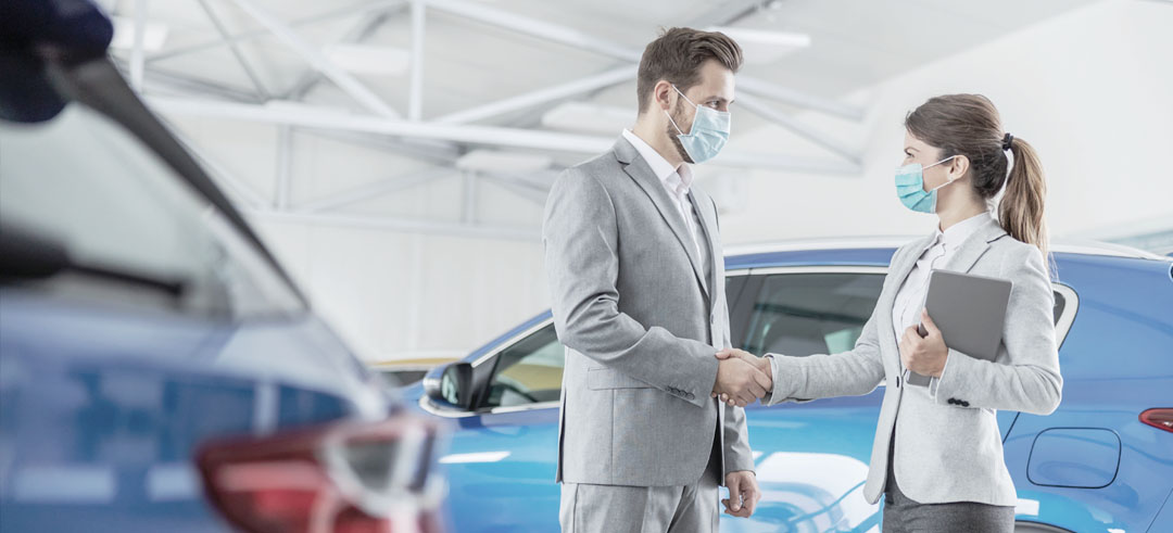 Dos personas dándose la mano en un concesionario de coches