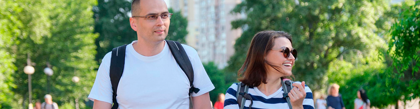 Dos persona caminando por un parque con mochilas puestas
