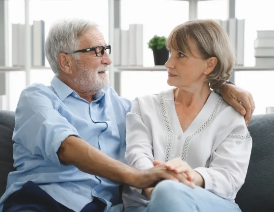 Pareja anciana sentados en el sofá de su casa y dándose las manos