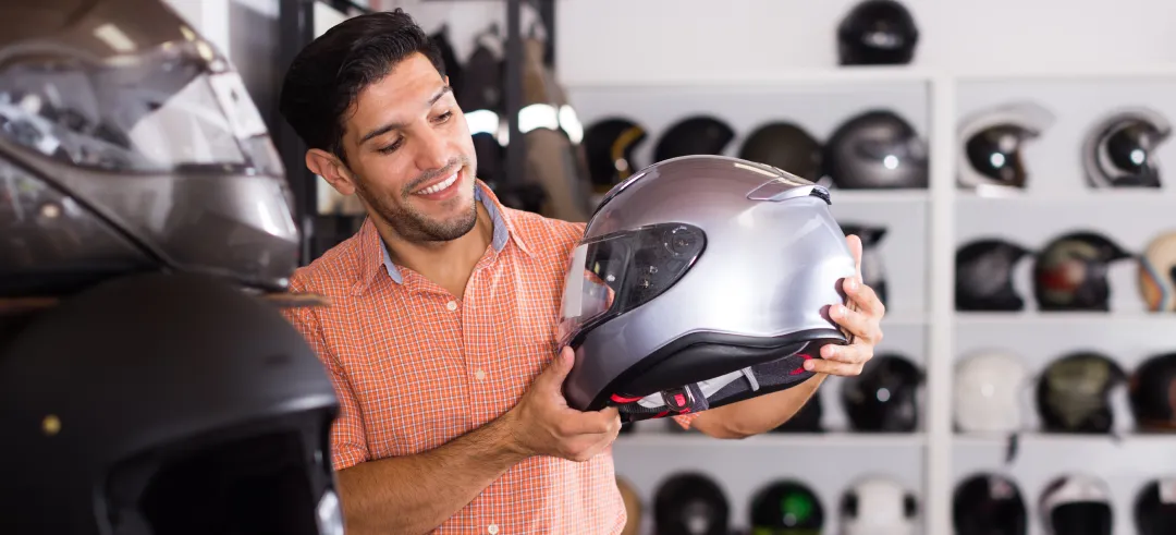 Hombre observando un casco de moto sujetado por sus manos