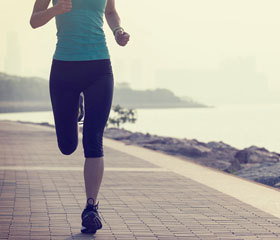 Mujer corriendo por un paseo marítimo cerca de la playa